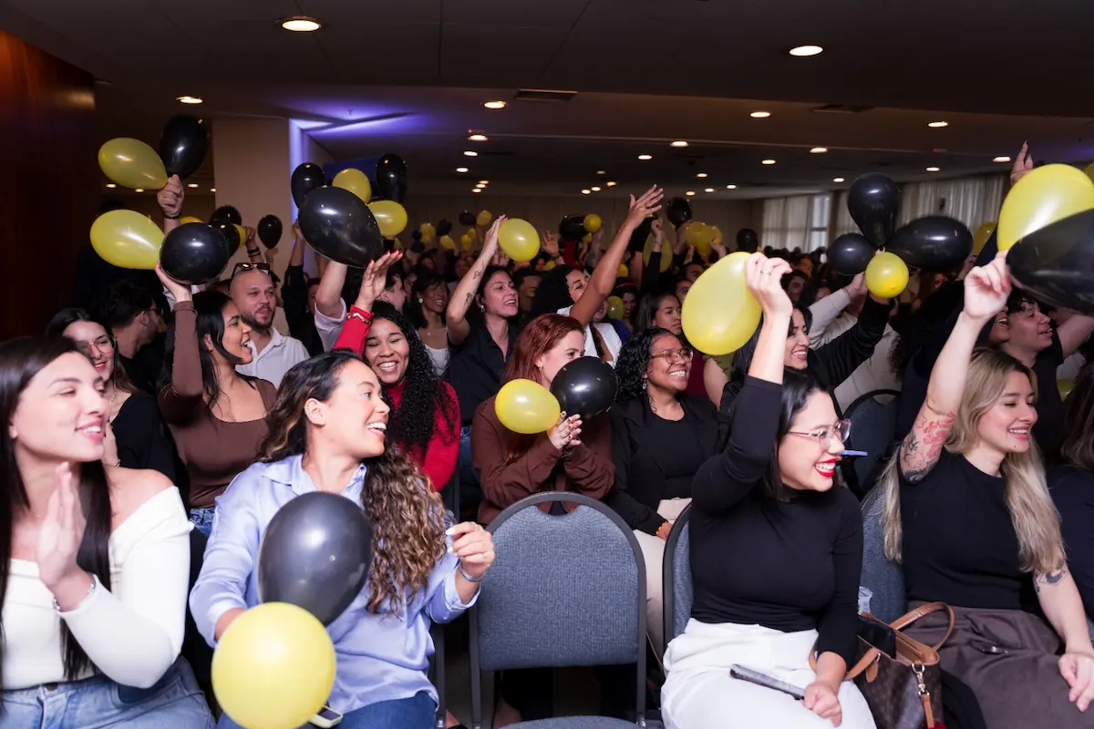 Plateia celebrando com balões amarelos e pretos